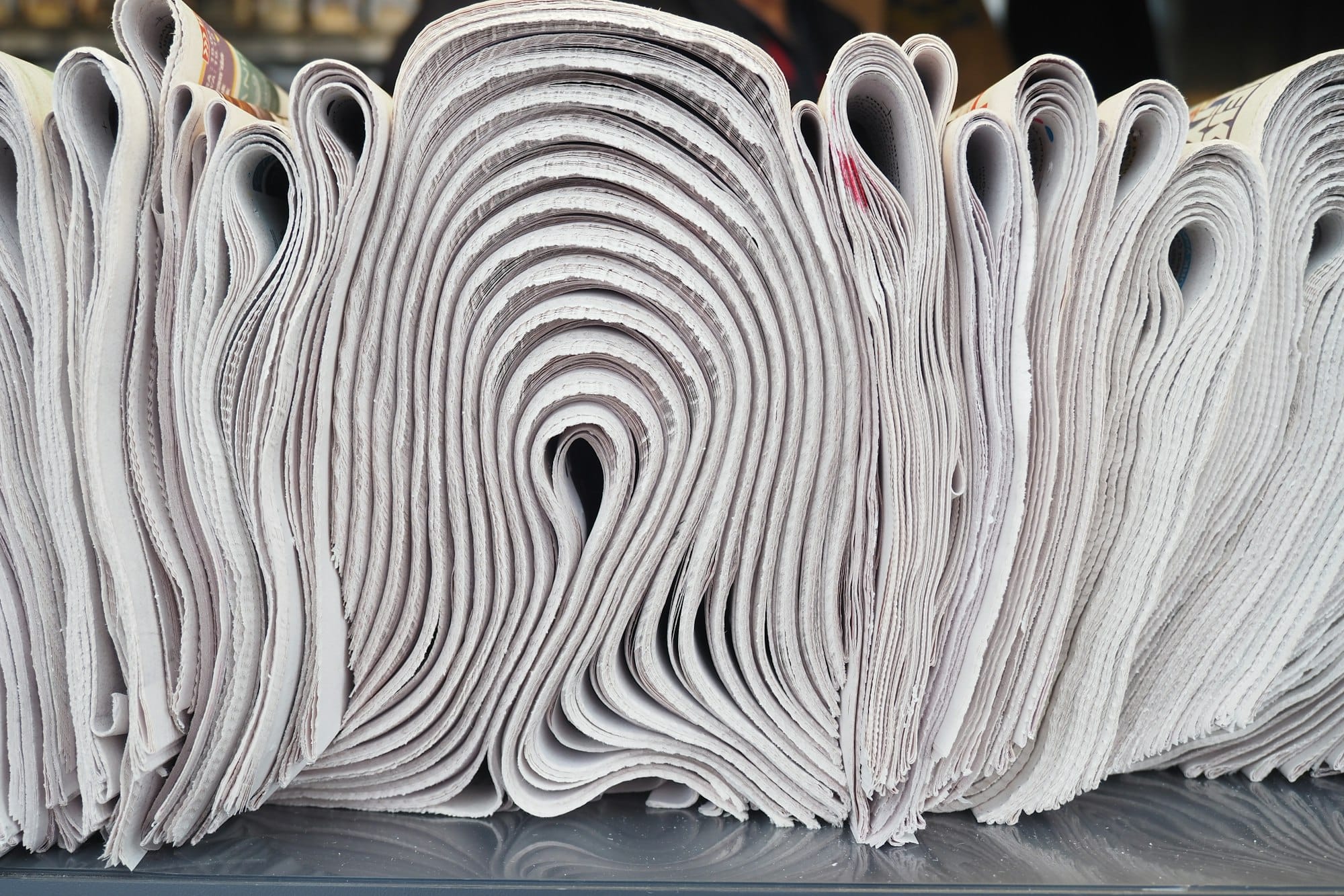 Pile of newspapers stacks on table .